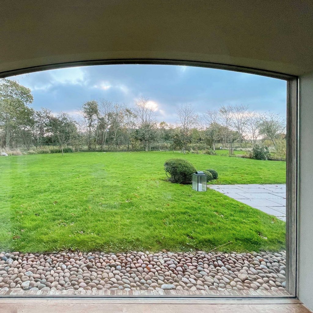 Luxus Ferienhaus auf der Nordseeinsel Föhr: Fenster vom Esstisch mit Blick in den Garten